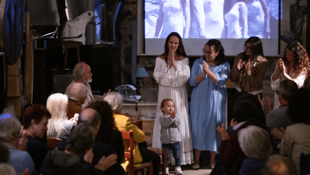 Gruppo di donne e un bambino sul palco applauditi dal pubblico.